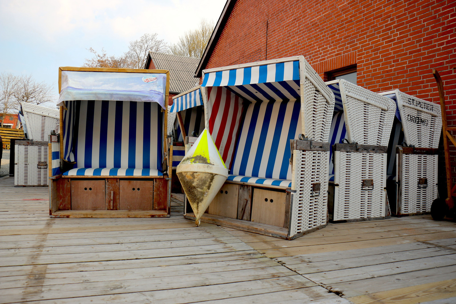 Strandk&ouml;rbe stehen gesammelt vor einem roten Backsteingeb&auml;ude.